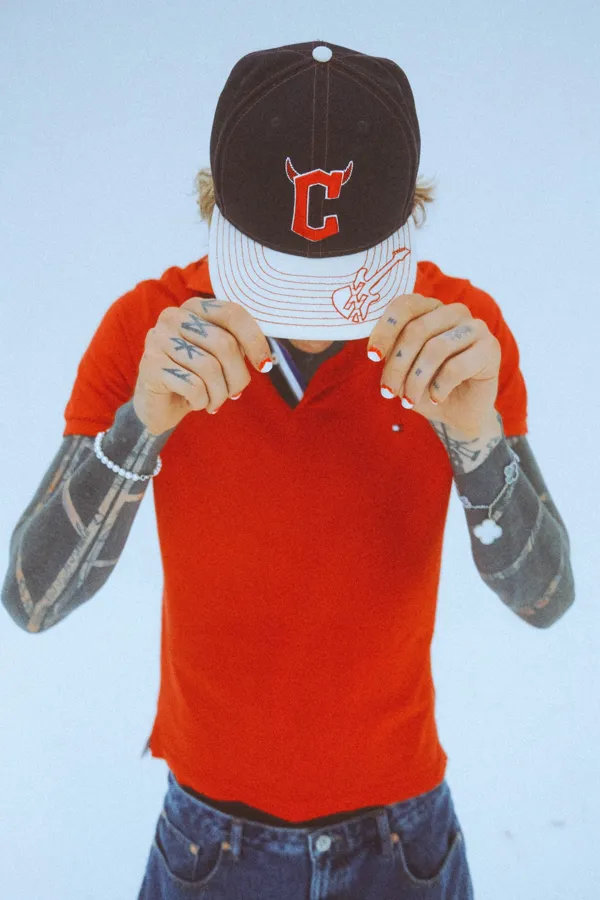 mgk x Cleveland Guardians cap with a red polo. Photo by Sam Cahill